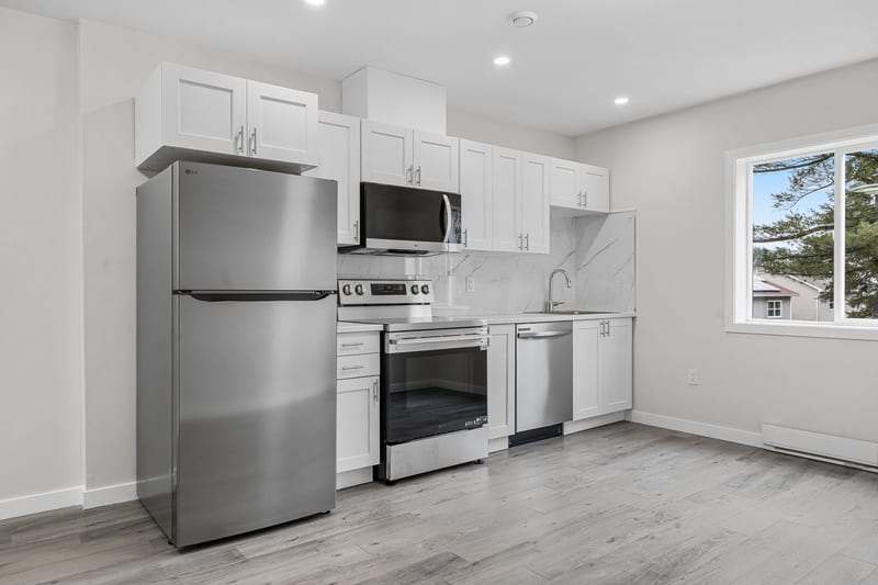 The kitchen: stainless appliances, white cabinets, the stone-look splashback